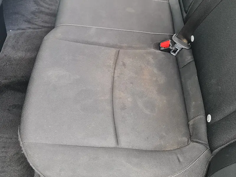 Zdjęcie tylnej kanapy samochodu z brudnymi siedzeniami.