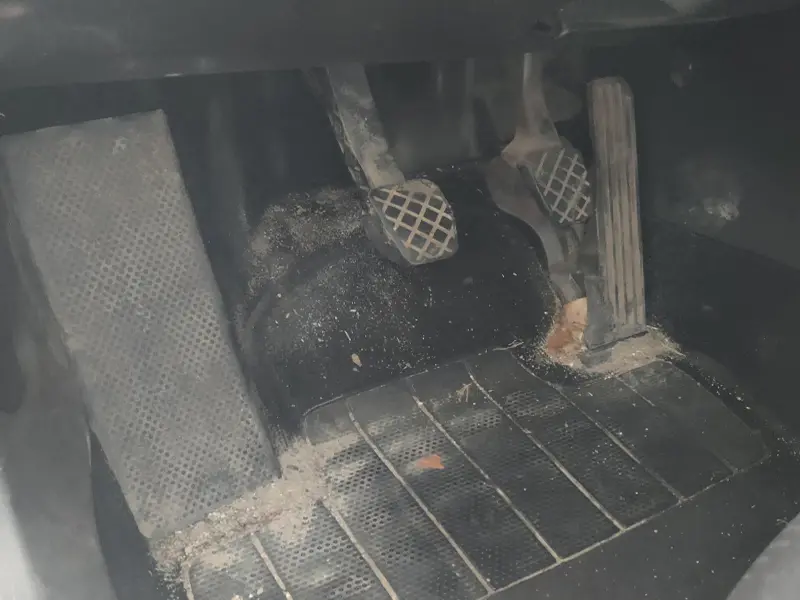 Brudne wnętrze samochodu z zabrudzoną podłogą.